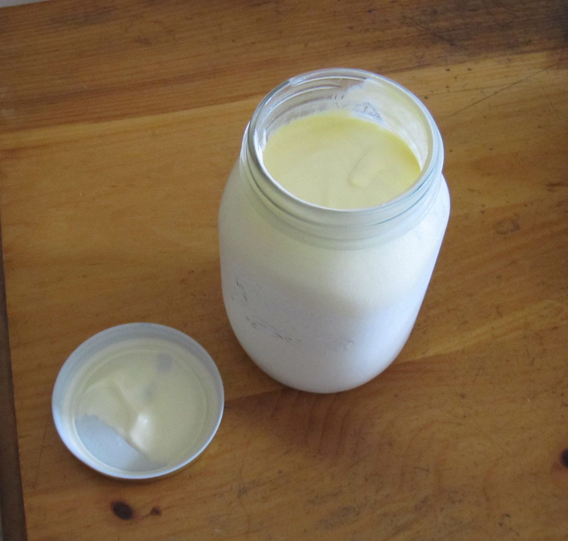 A Mason jar of fermented raw cow's milk kefir on a table with the top off.