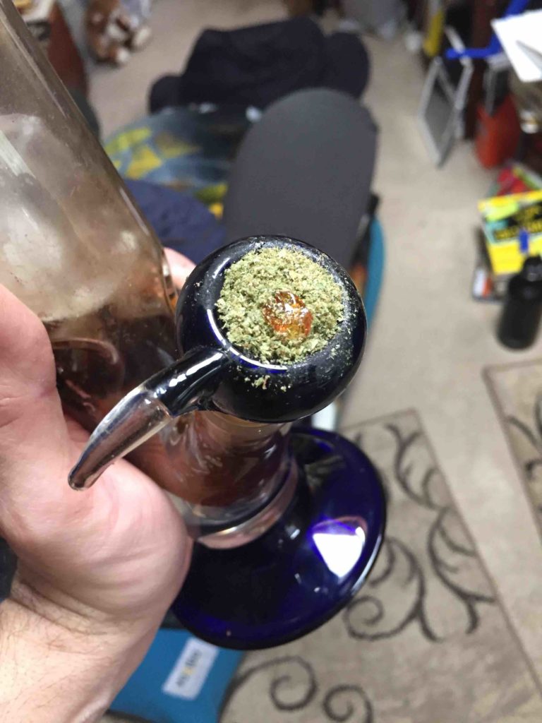 Picture of medical marijuana flower in bong with small amount of AGL Shatter concentrate in top of flower.