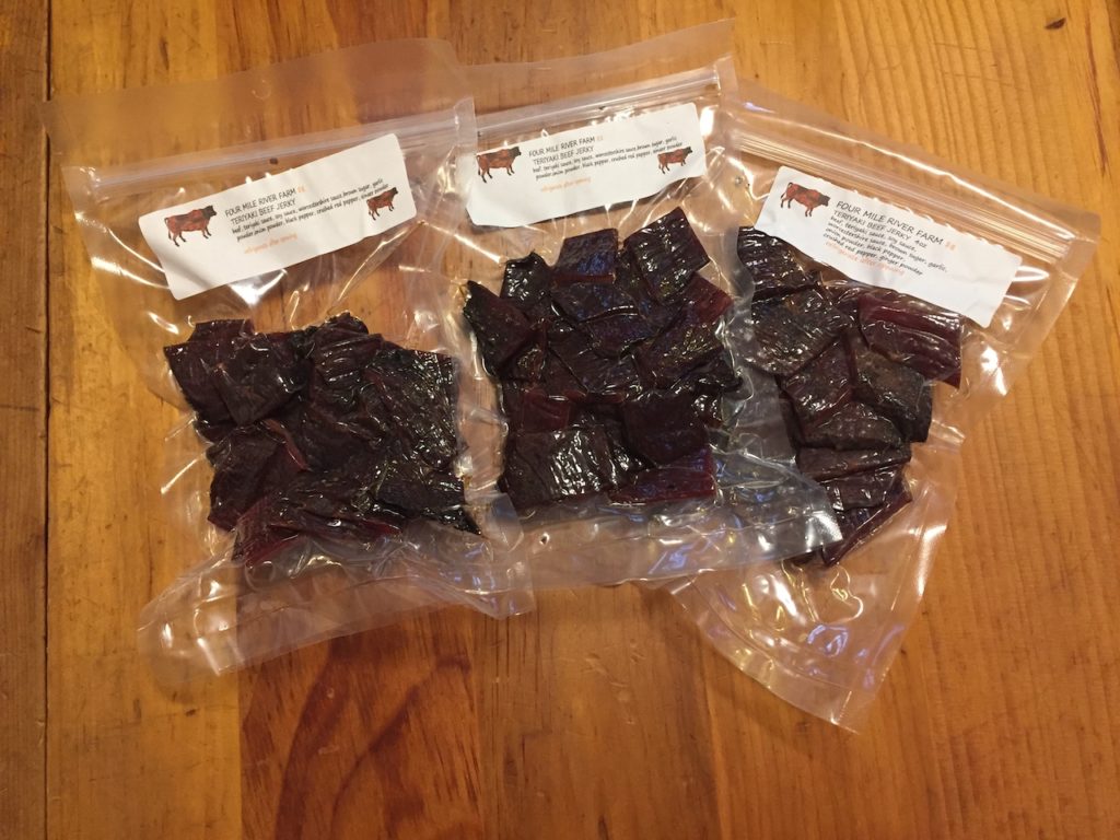 Three packages of beef jerky on a table.