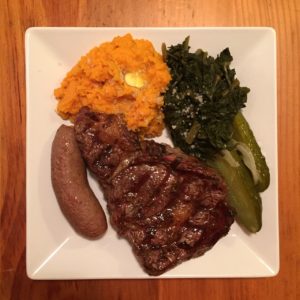 A rib-eye steak, braised kale, sweet potato and pickles.