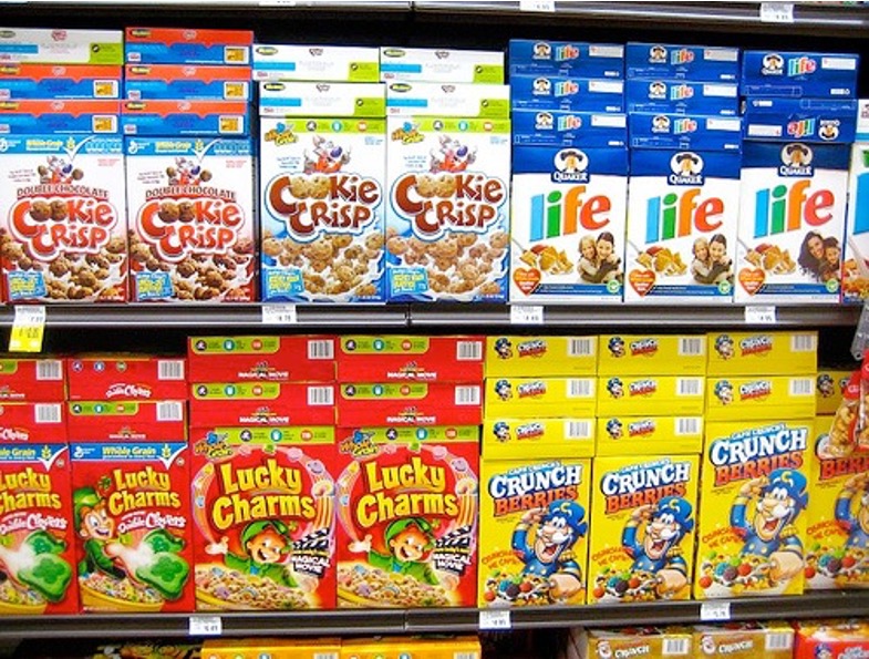 Sugary cereals in colorful boxes on a supermarket shelf.