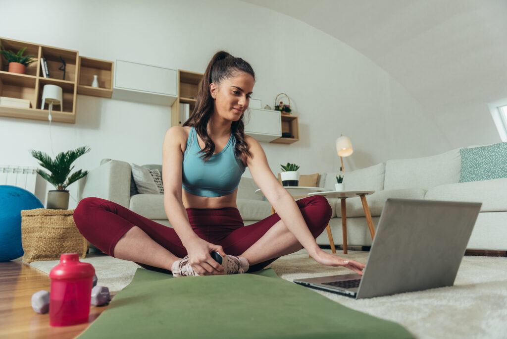 Shot of a woman training at home while using a laptop for online class